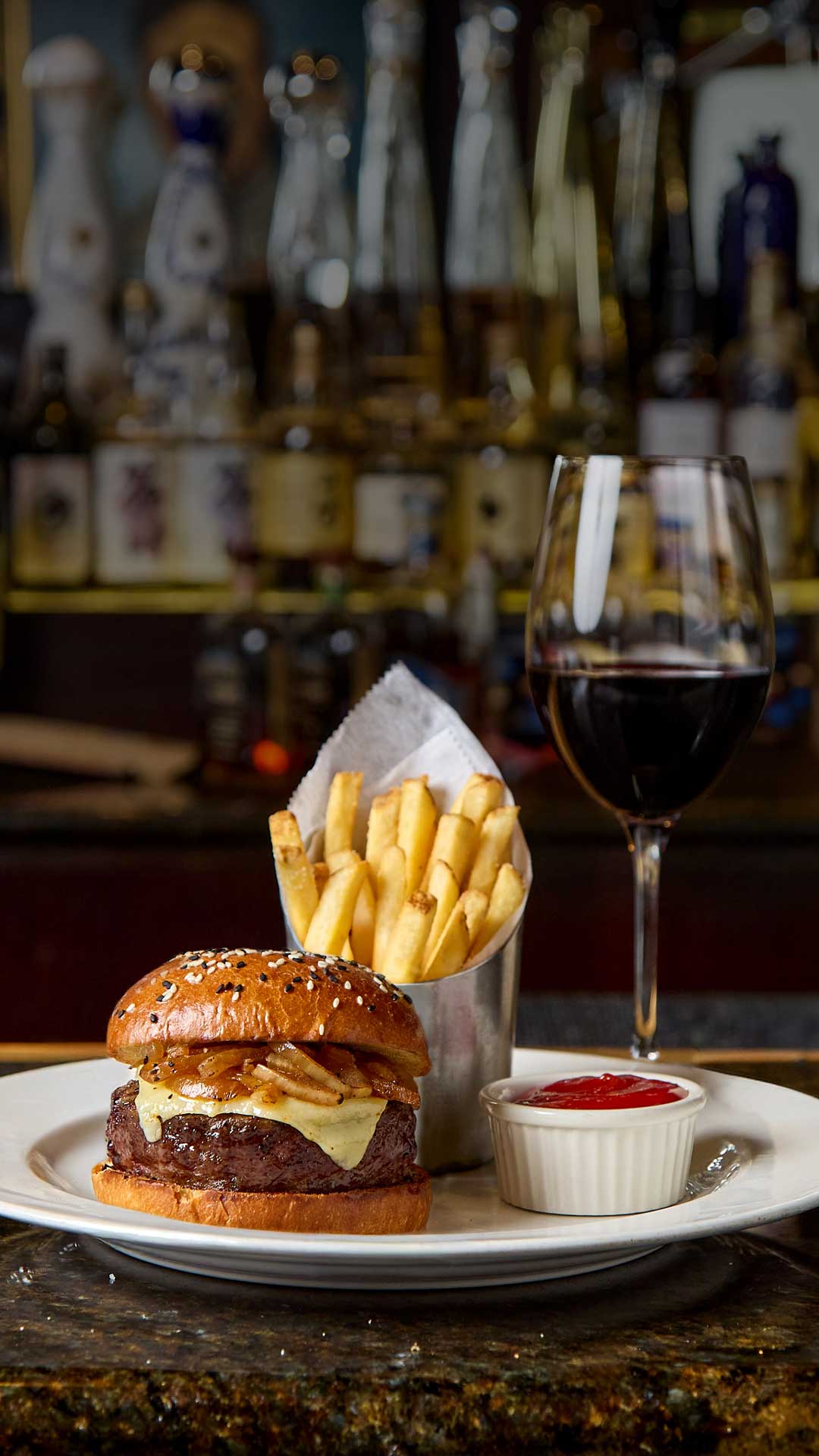 Wagyu burger and red wine pairing at The Capital Grille, featuring a signature burger, fries, and a glass of red wine in an elegant restaurant setting.